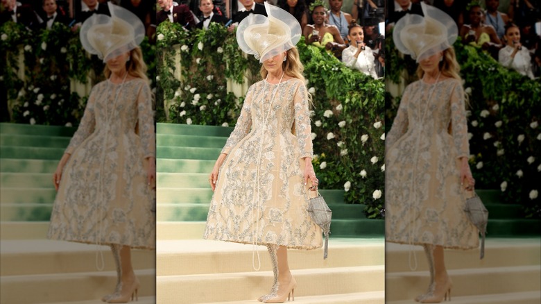 Sarah Jessica Parker posing at the Met Gala in 2024 in an intricate gold dress with a large hat.