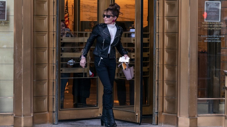 Sarah Palin leaves a building in a leather jacket, black pants, leather boots, and with her hair pinned up