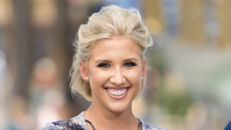 Savannah Chrisley smiles into the camera. She is a young white woman with wavy blonde hair cut into a bob.