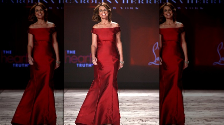 Savannah Guthrie walks down a fashion show runway in a red dress