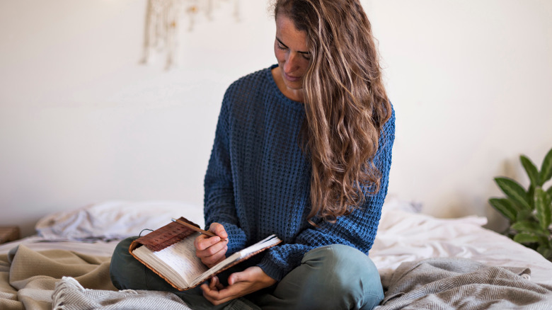 Woman writing in journal on bed