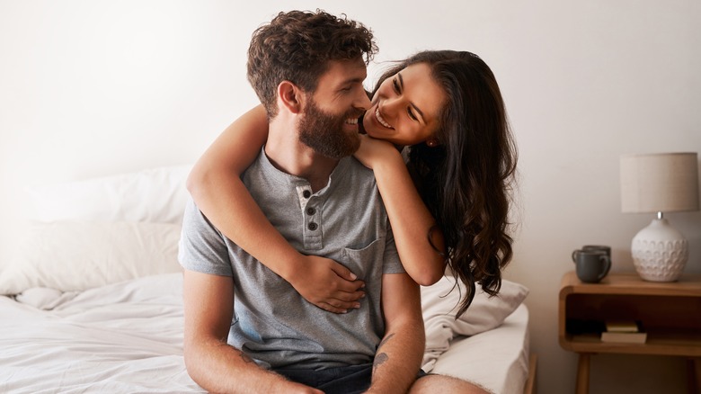 Smiling couple hugging in bedroom