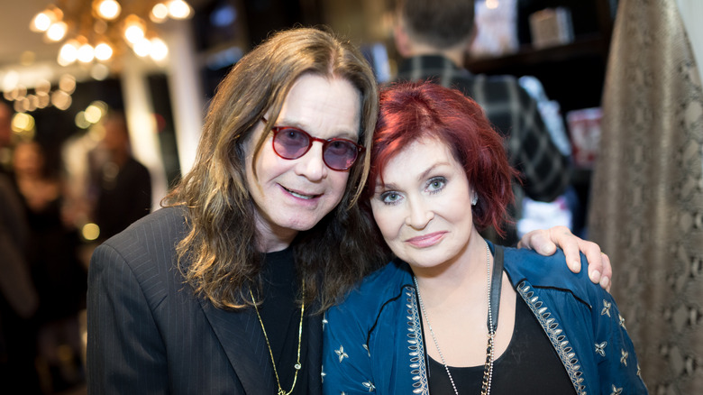 Ozzy Osbourne smiles as he puts his arm around Sharon Osbourne