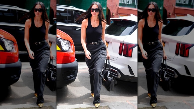 Dua Lipa wearing a black scoop-neck tank top and black trousers.