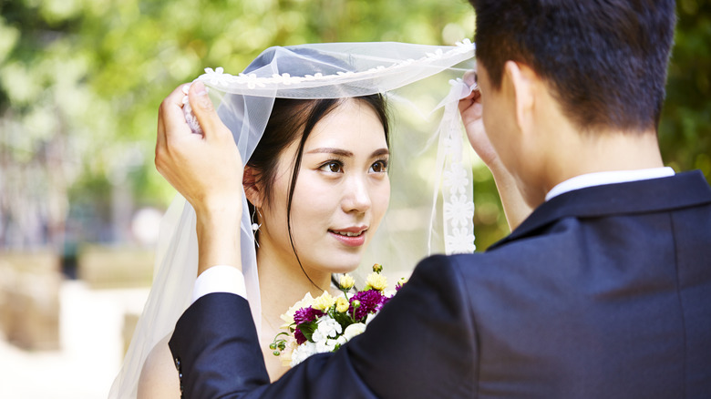 groom lifting the veil to kiss bride