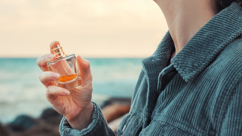 Woman spraying perfume outdoors