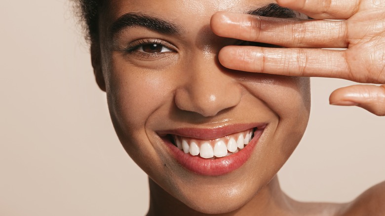 smiling woman covering eyelid