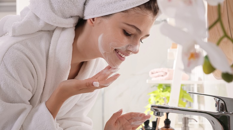 woman in bathrobe cleansing her face