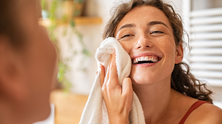 smiling woman wiping face with towel