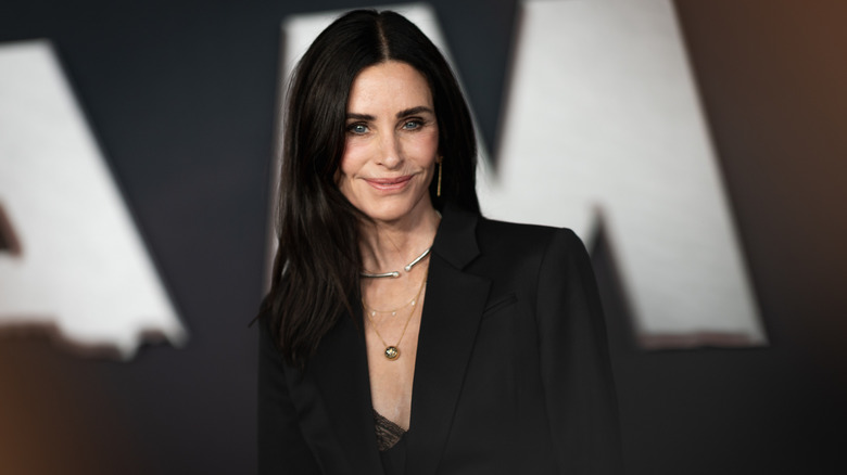 Courteney Cox smiling in a black blazer