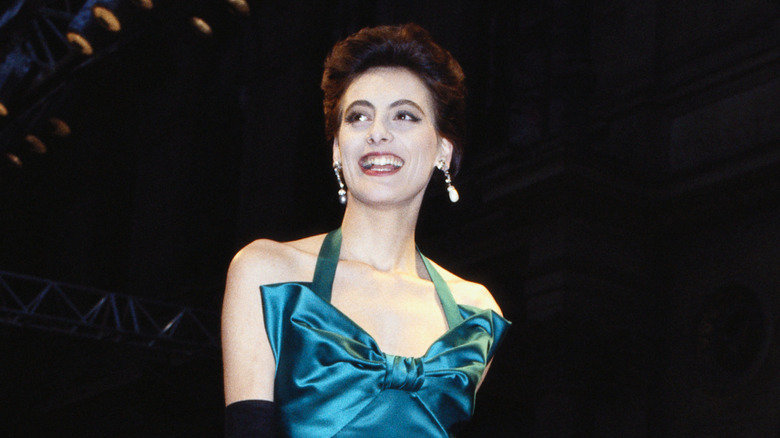Inès de la Fressange smiles on the runway wearing a blue bow dress
