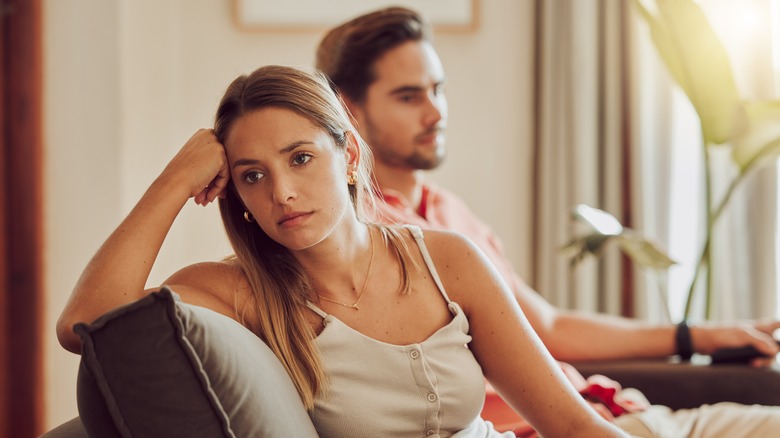 Sad woman on couch with partner