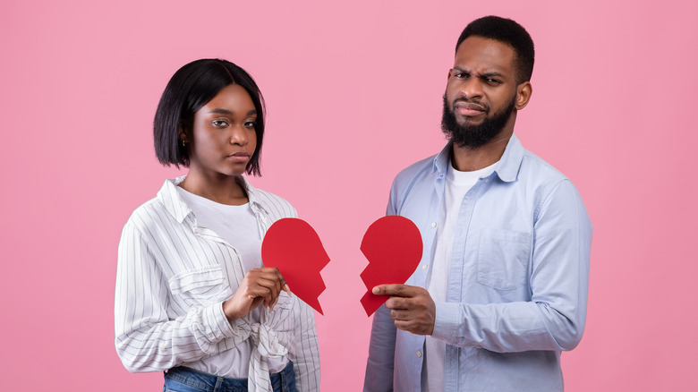 unhappy couple holding hearts 