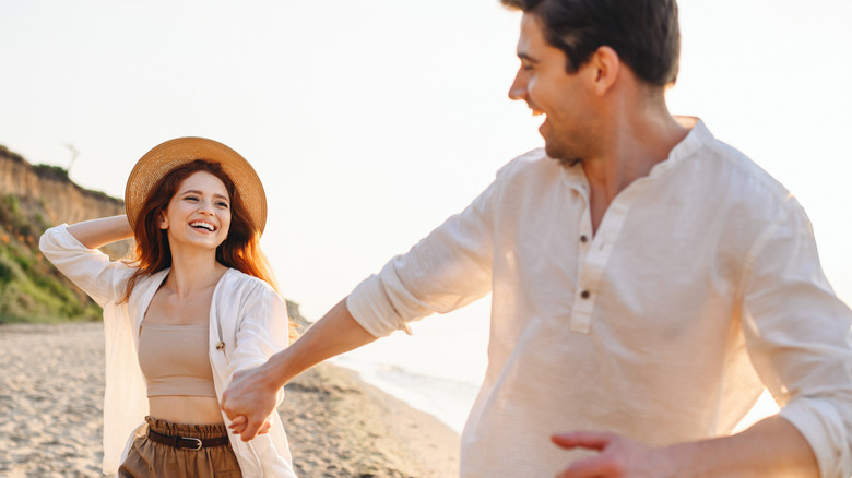 Happy couple holding hands on beach