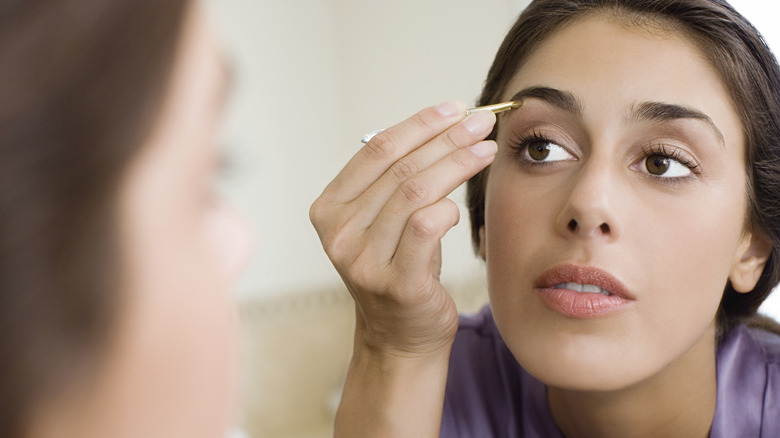 Woman tweezing her eyebrows