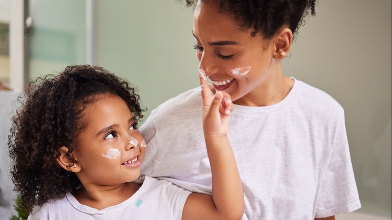 Woman, child applying facial lotion