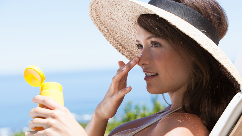 A woman applying sunscreen to her face
