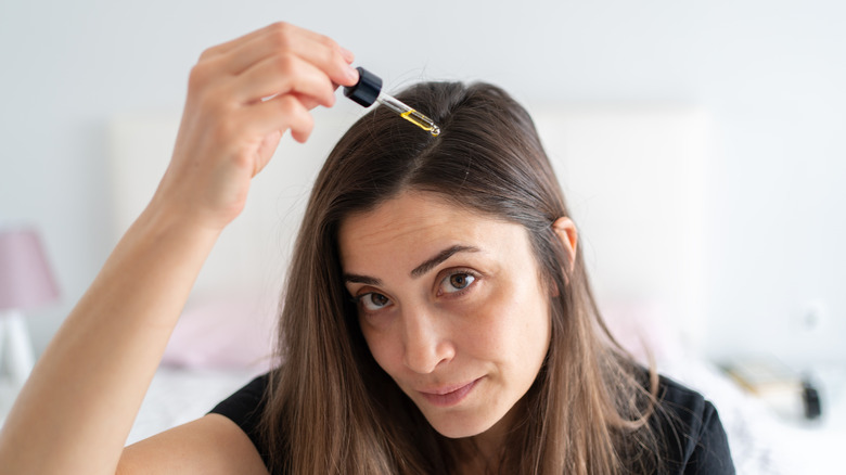 Woman applying serum to her hair
