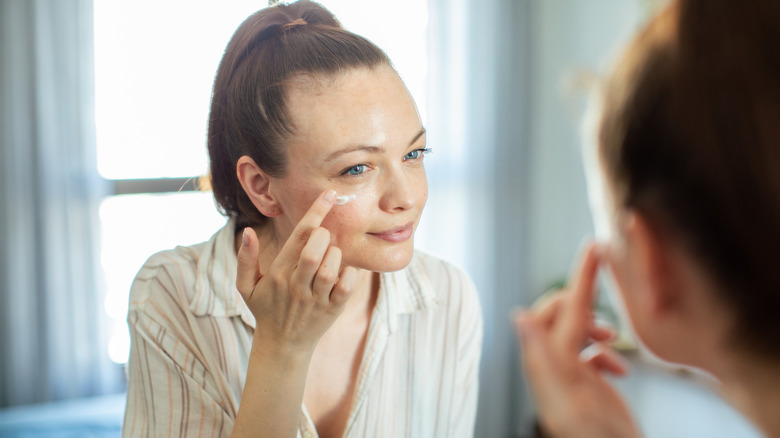 A woman applying a moisturizing cream to her face