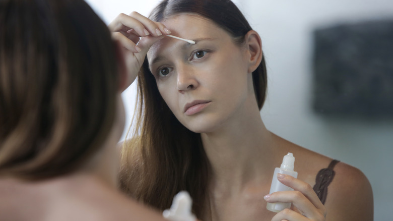 woman applying serum to eyebrows