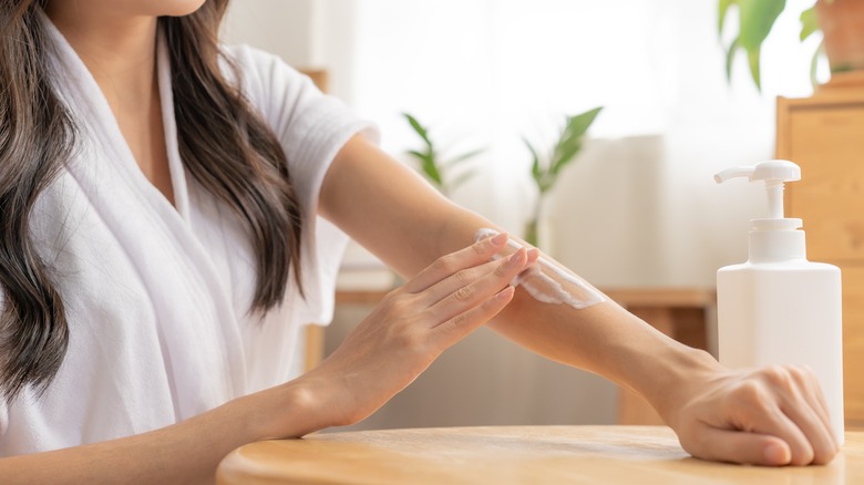 Woman applying lotion to her skin