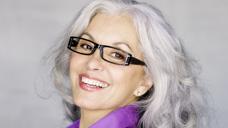 A mature woman wearing narrow, rectangular glasses.
