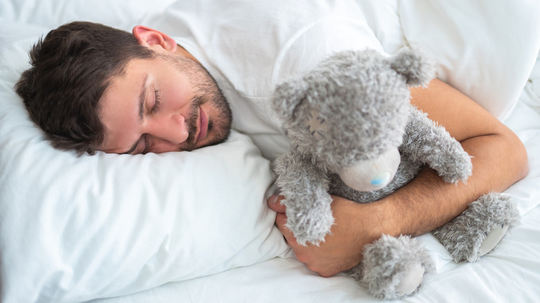 man sleeping with a stuffed animal