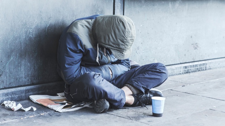 Homeless man sitting on sidewalk