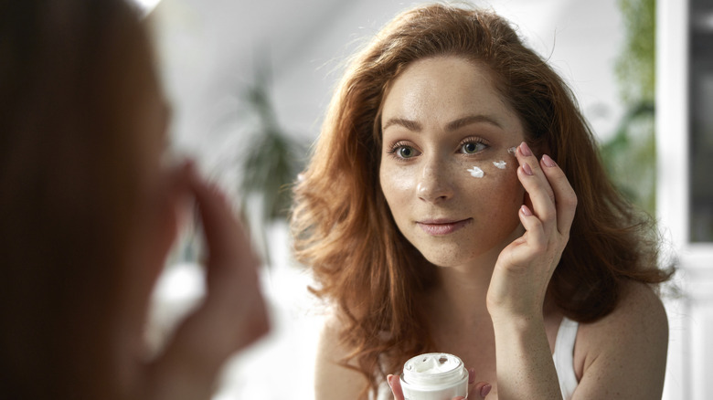 woman applying skincare to face