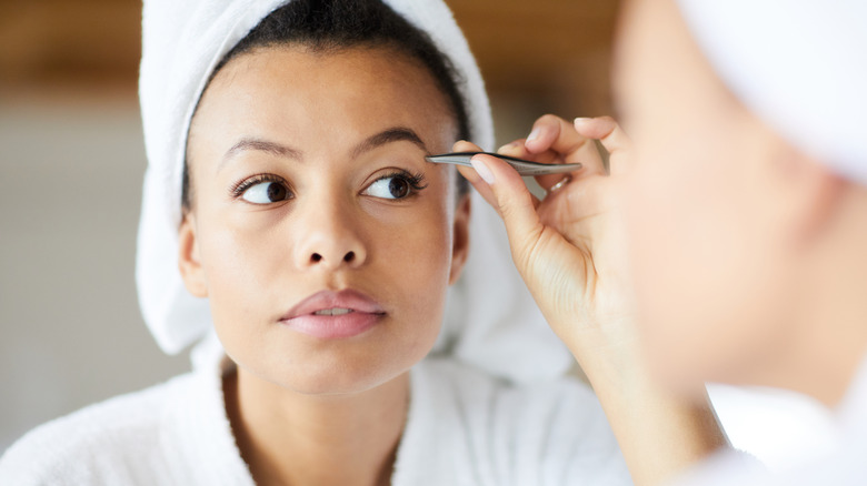 woman tweezing eyebrows