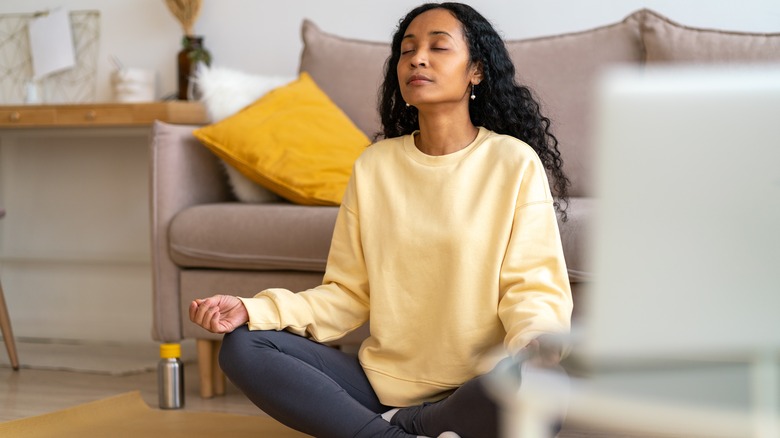 Woman practices somatic breathwork near laptop 