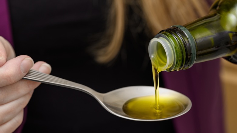 Close up image of olive oil being measured in a tablespoon.