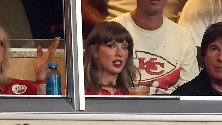 Taylor Swift with her hair in light curls sitting beside Tom Cruise at the Kansas City Chiefs game against the Denver Broncos