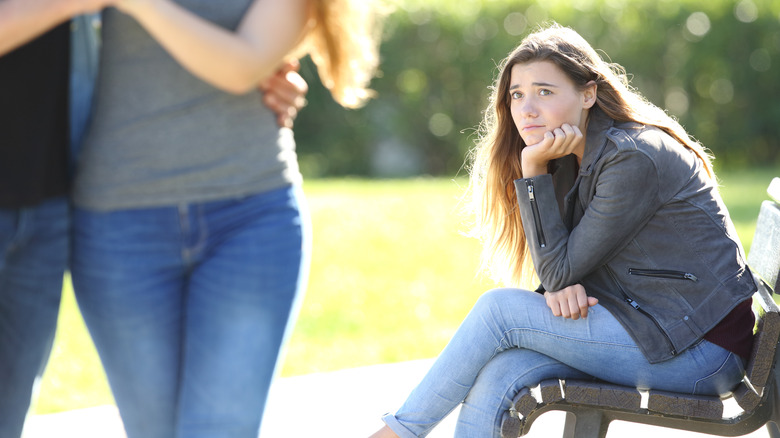 Woman sitting outside watching couple