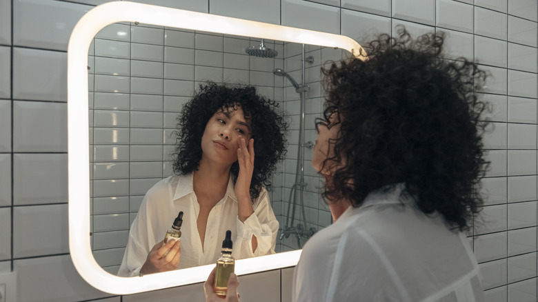 woman applying skincare in bathroom