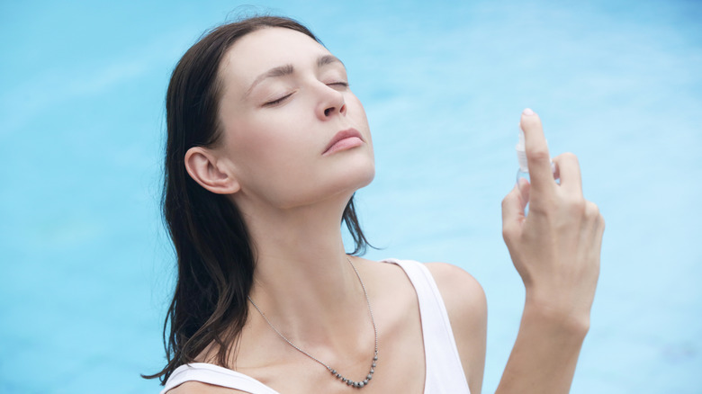Woman misting on skincare in pool