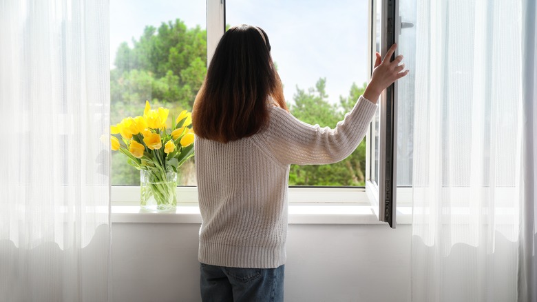 Person standing by open window