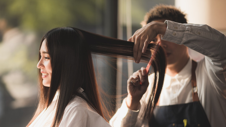 woman having straight hair combed at salon