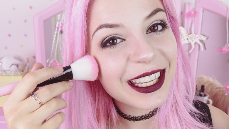 Woman applying pink makeup
