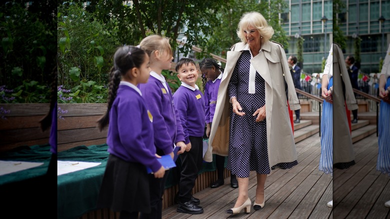 Queen Camilla walking with a trench draped over her shoulders