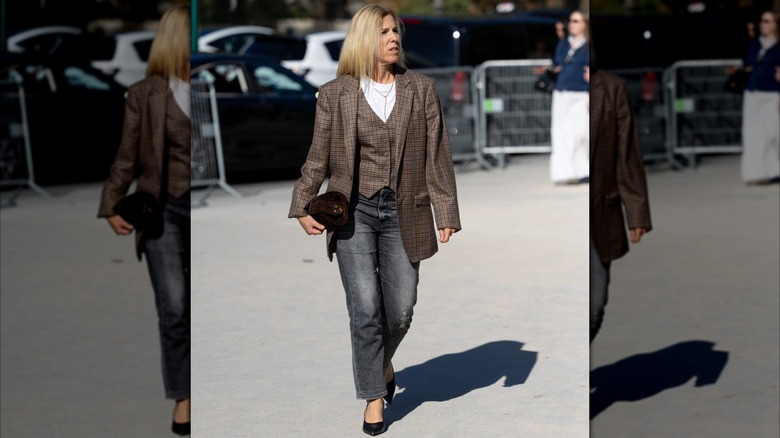 A woman wearing a vest and blazer with jeans and a tee