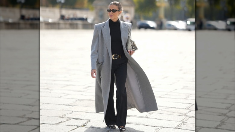 A woman wearing a structural bag and sunglasses