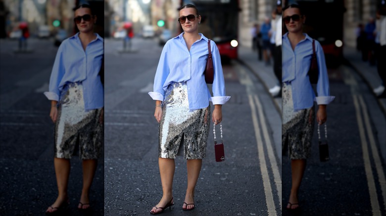 A woman with her button up tucked half-way into her skirt