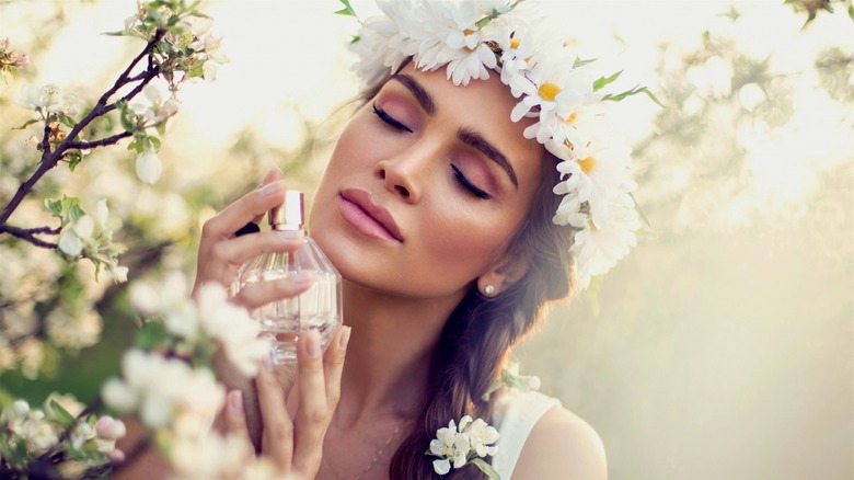 woman with floral crown holds perfume