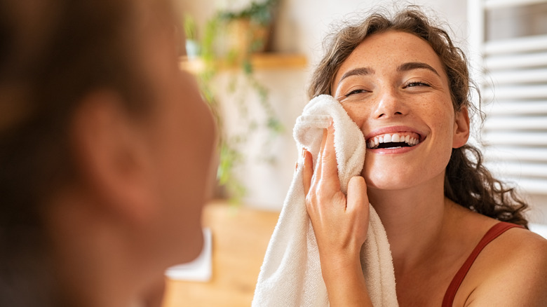 Woman smiling, wiping face with towel