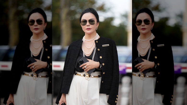 An older woman accessorizing with statement beaded necklaces