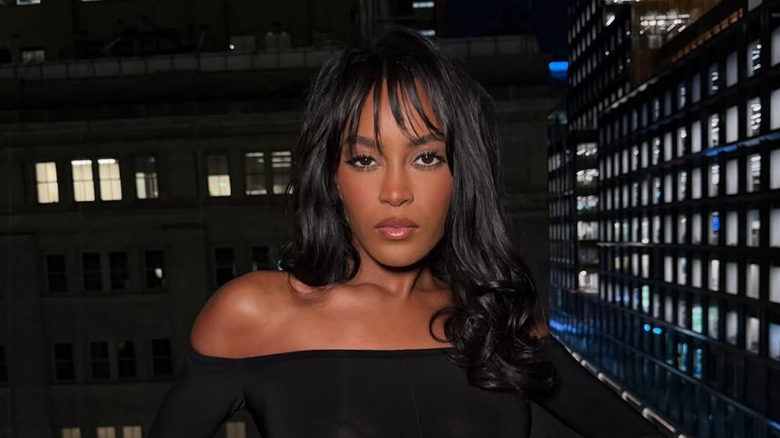 Ciara Miller posing with curly hair and wispy bangs