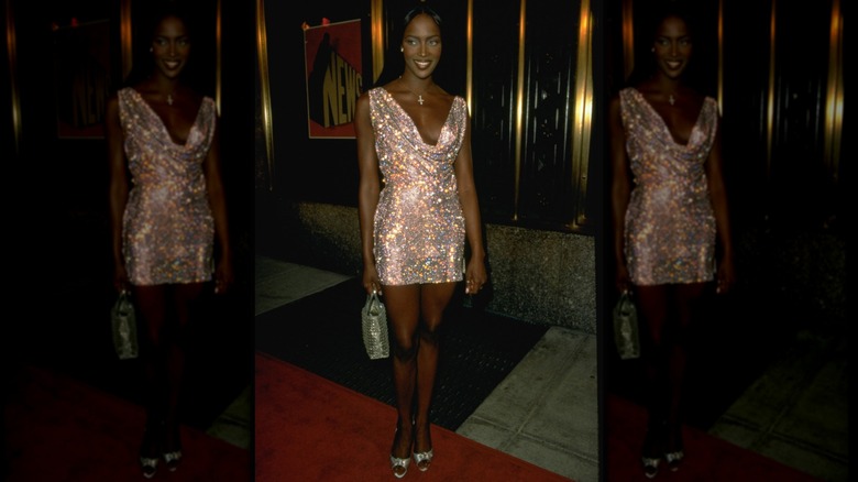 Naomi Campbell wearing a sparkly cowl-neck minidress.