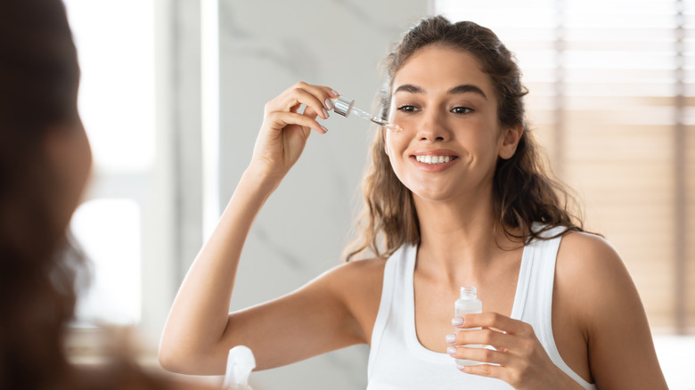 woman applying serum to face