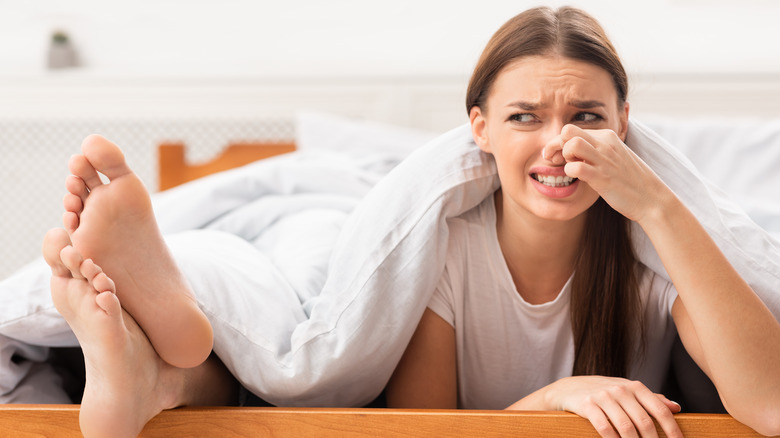 Woman pinching nose at stinky feet